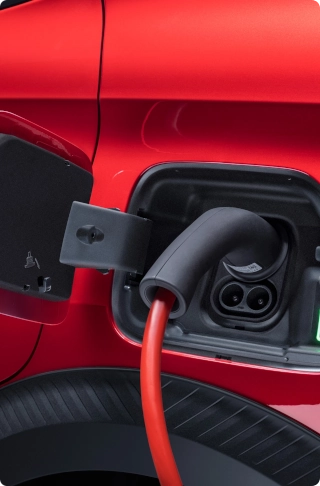 Vista de detalle del puerto de carga del Citroën ë-C3 Comercial conectado a un cable de carga, destacando la movilidad eléctrica y la recarga práctica.