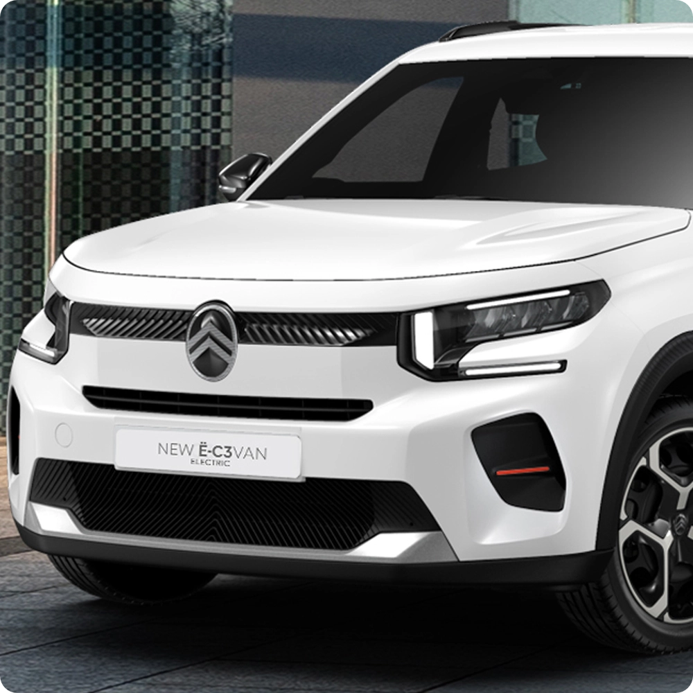 Vista frontal tres cuartos del Citroën ë-C3 Comercial aparcado en un entorno urbano, destacando su diseño moderno y sus proporciones compactas.