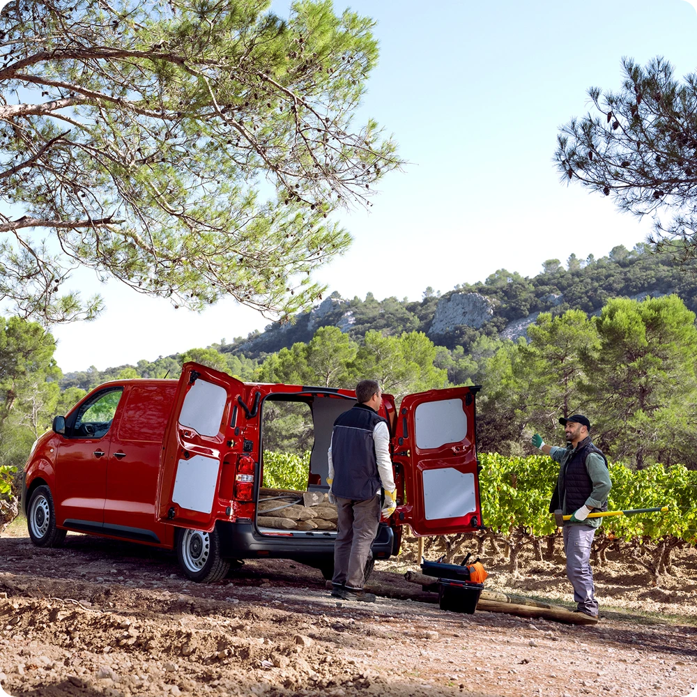 Vista exterior tres cuartos trasera de un Citroën Jumpy rojo con las puertas traseras abiertas durante la carga, mostrando espacio de carga versátil, acceso práctico e idoneidad para uso profesional.