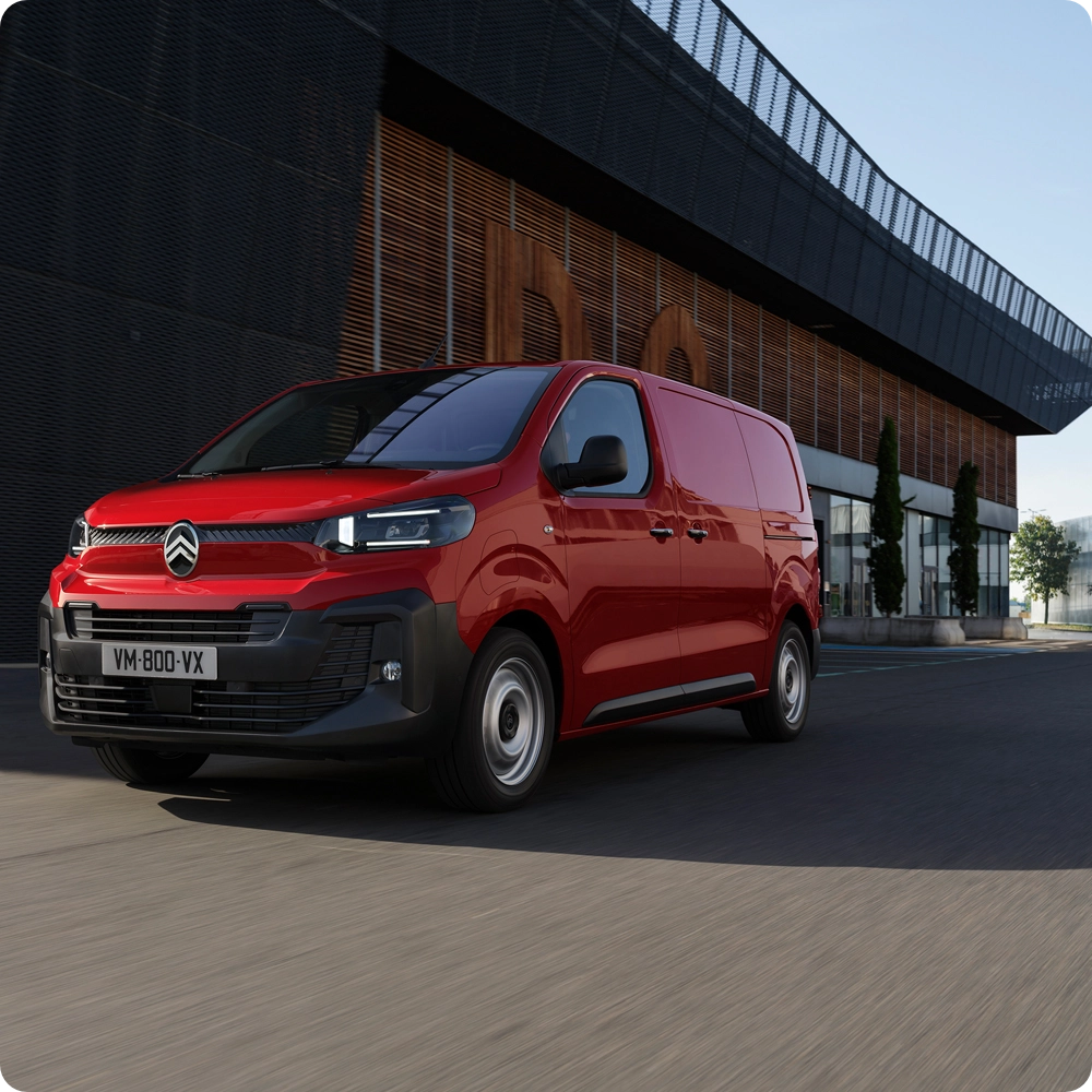 Vista frontal tres cuartos de un Citroën Jumpy rojo circulando en un entorno urbano, mostrando diseño moderno, confort de conducción, conectividad y presencia profesional segura.