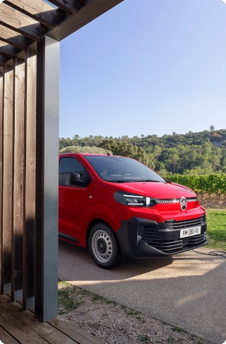 Vista exterior tres cuartos trasera de un Citroën Jumpy rojo siendo cargado con mercancías, mostrando diseño robusto, uso diario intensivo y acceso práctico a la carga.