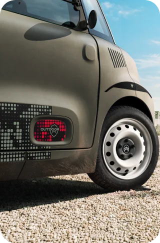 Primer plano de las llantas de acero blancas del Citroën Ami Outdoor, un vehículo eléctrico compacto para la movilidad diaria.