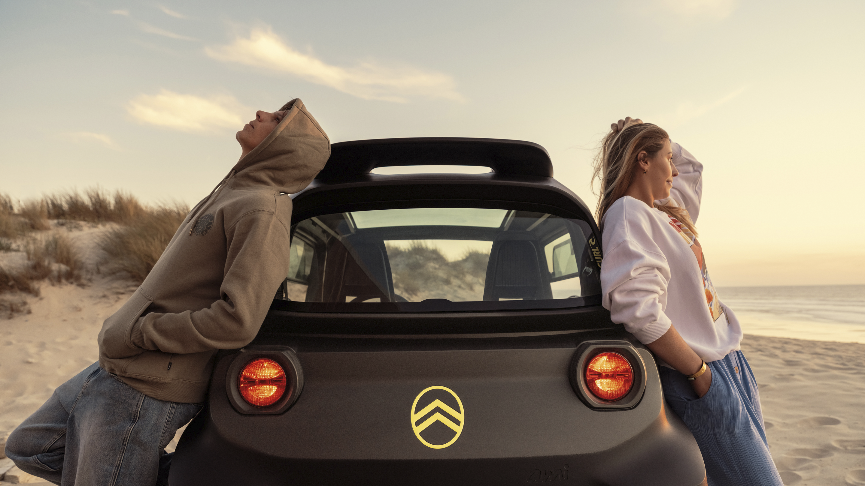 Vista lifestyle trasera atardecer del Citroën Ami x Rip Curl eléctrico sin carné, libertad relajada Citroën Ami para coche eléctrico urbano