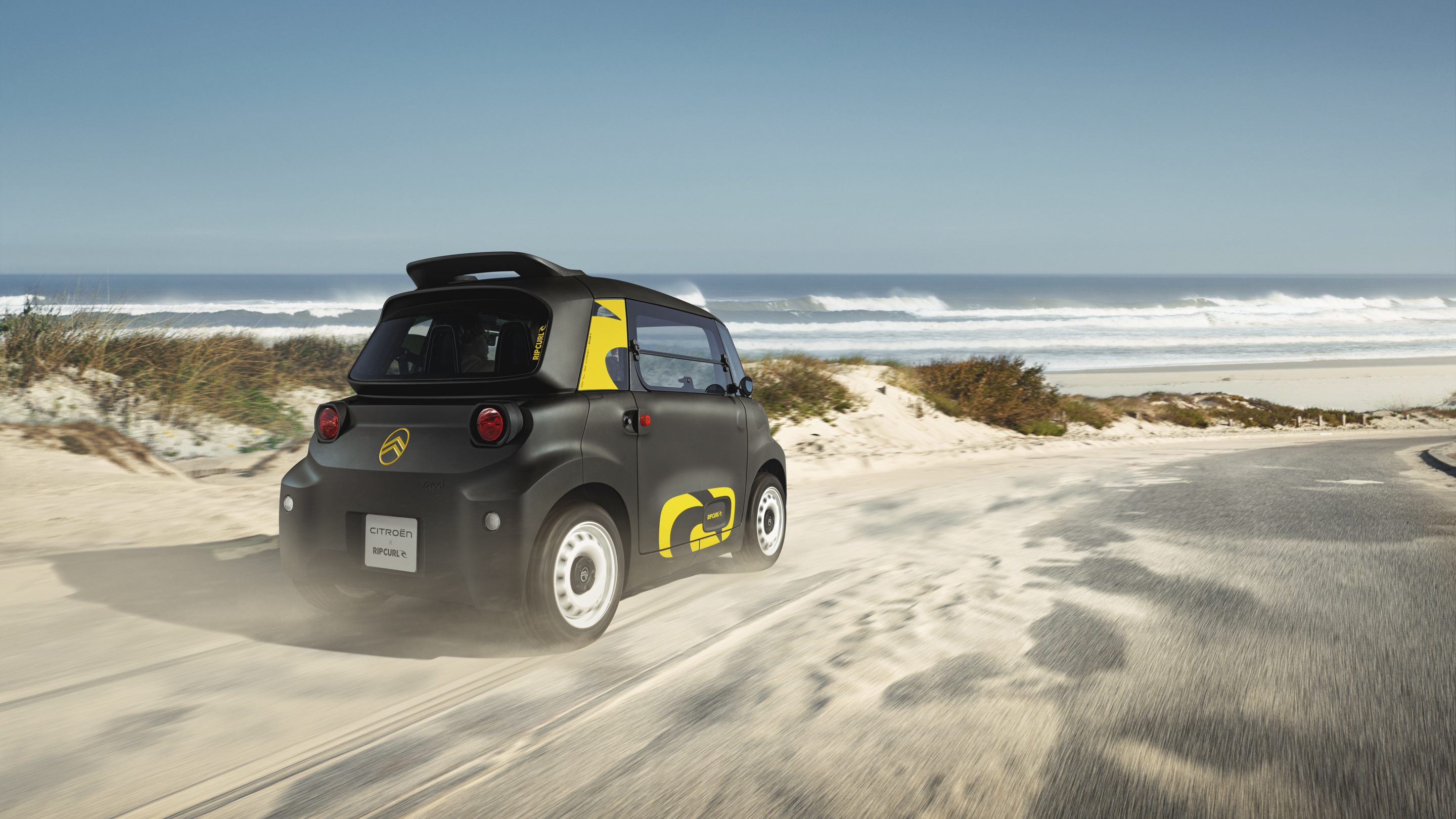 Vista trasera en tres cuartos en acción del Citroën Ami x Rip Curl eléctrico sin carné, Citroën Ami libertad para coche eléctrico urbano