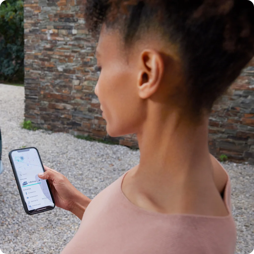 Persona usando un smartphone con la app Free2Move Charge, destacando la planificación de rutas y la guía a estaciones de carga para el Citroën ë-C3 Comercial.