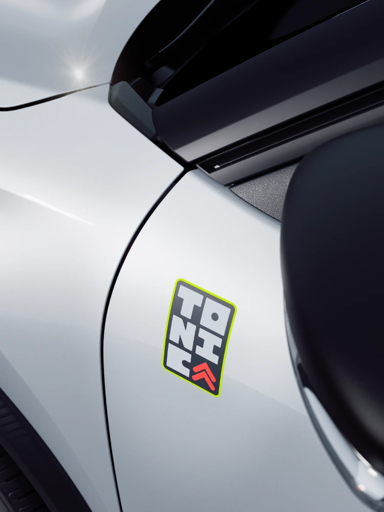 Vista detalle frontal del Citroën ë-C3 TONIC edición limitada, coche eléctrico urbano con parrilla característica y clips de color, alternativa electrica distintiva