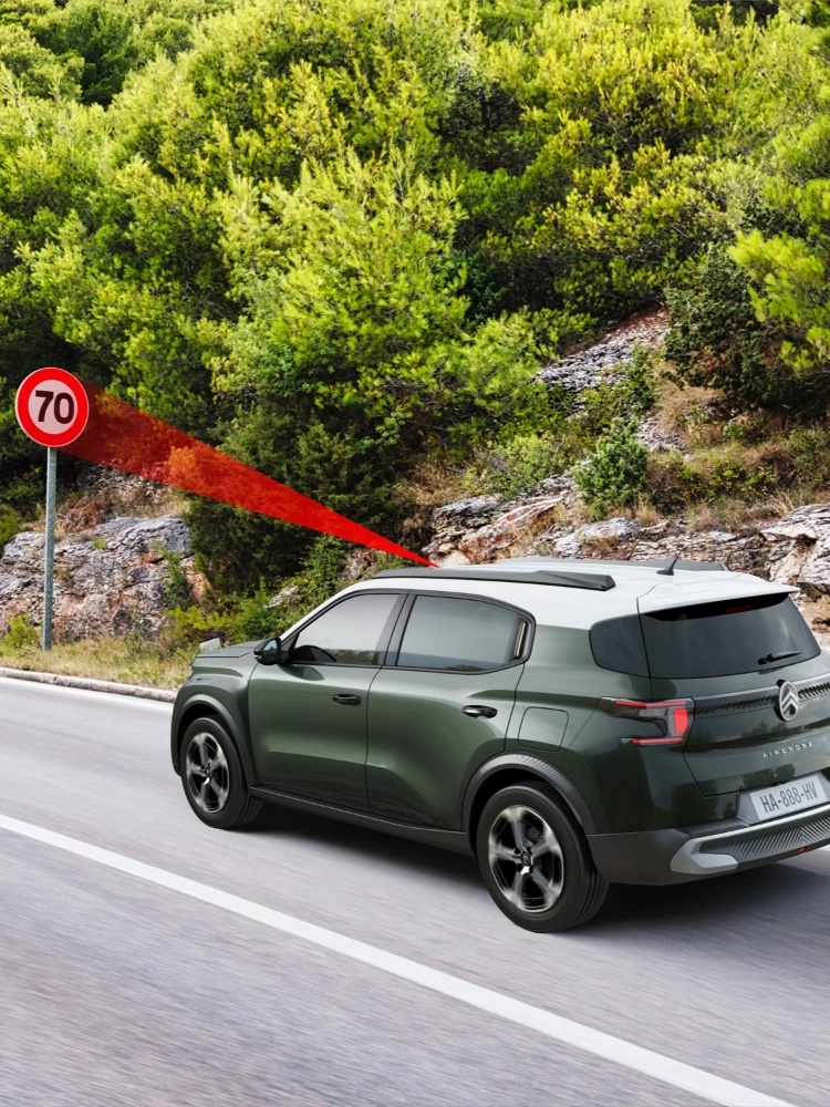 Vista lateral en conducción del Citroën ë-C3 Aircross SUV mostrando reconocimiento de límites de velocidad para una movilidad diaria más segura, informada y asequible.