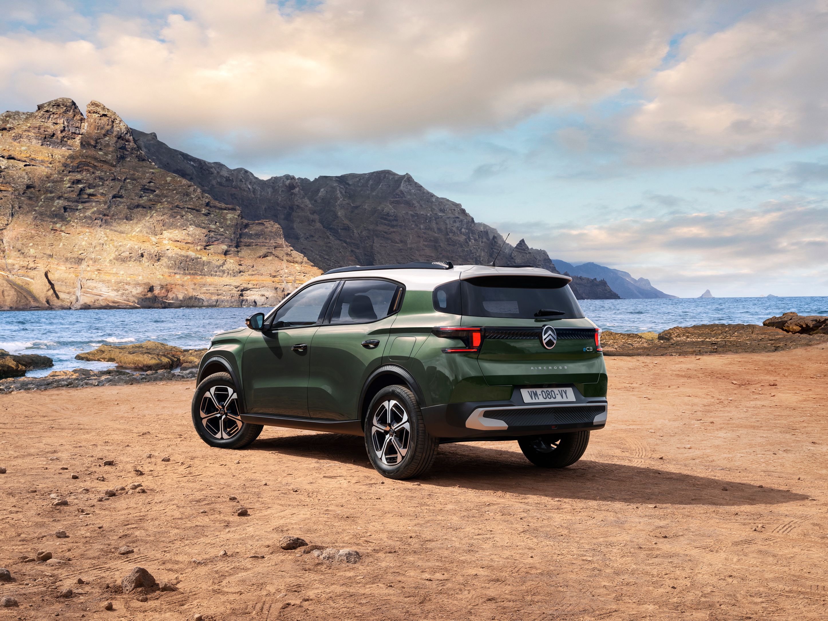 Vista trasera tres cuartos junto al mar del Citroën ë-C3 Aircross SUV mostrando diseño SUV moderno para una movilidad versátil y asequible.