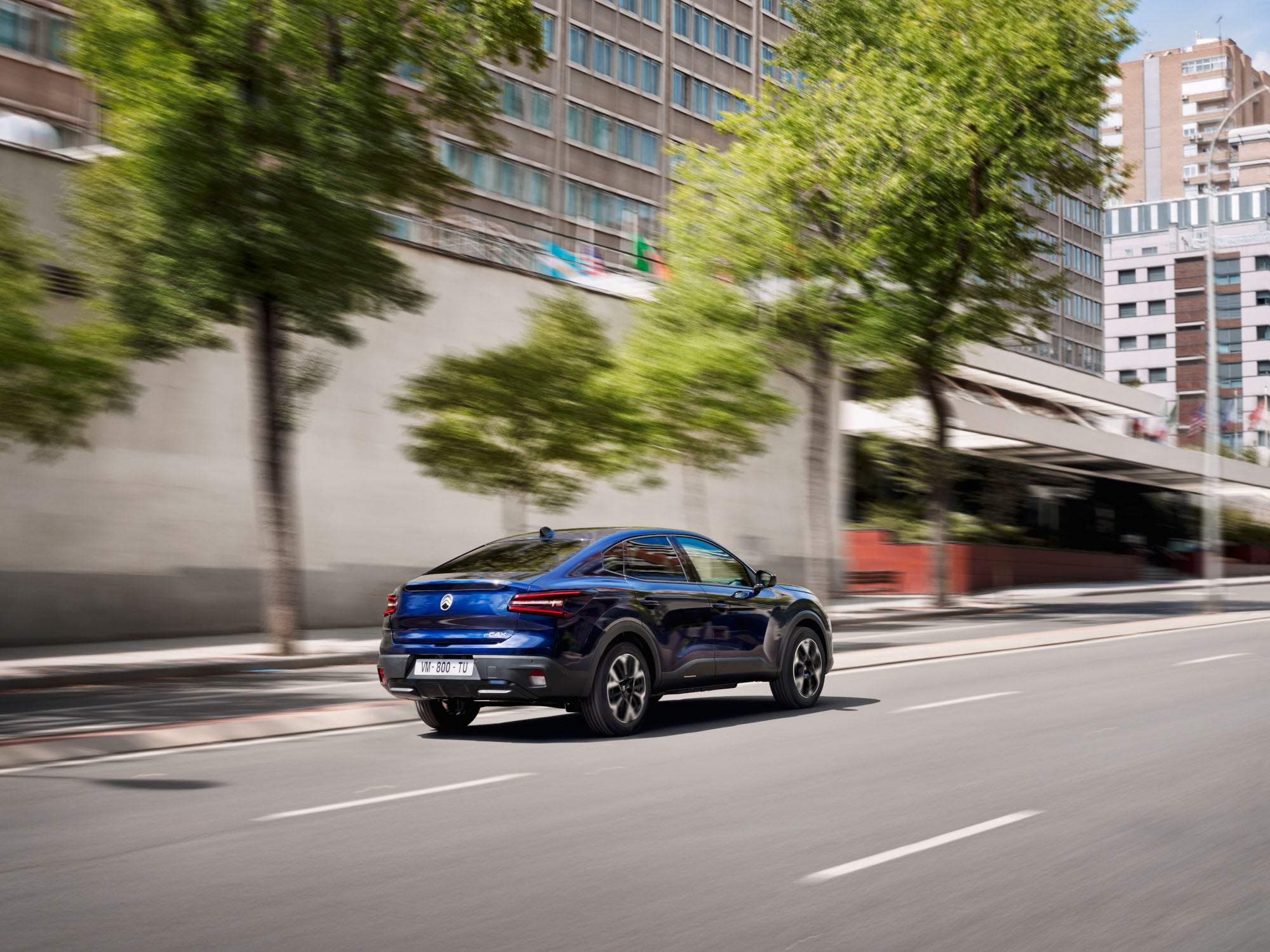 Vista trasera tres cuartos en conducción del Citroën C4 X destacando estilo fastback moderno para una movilidad eficiente y asequible.