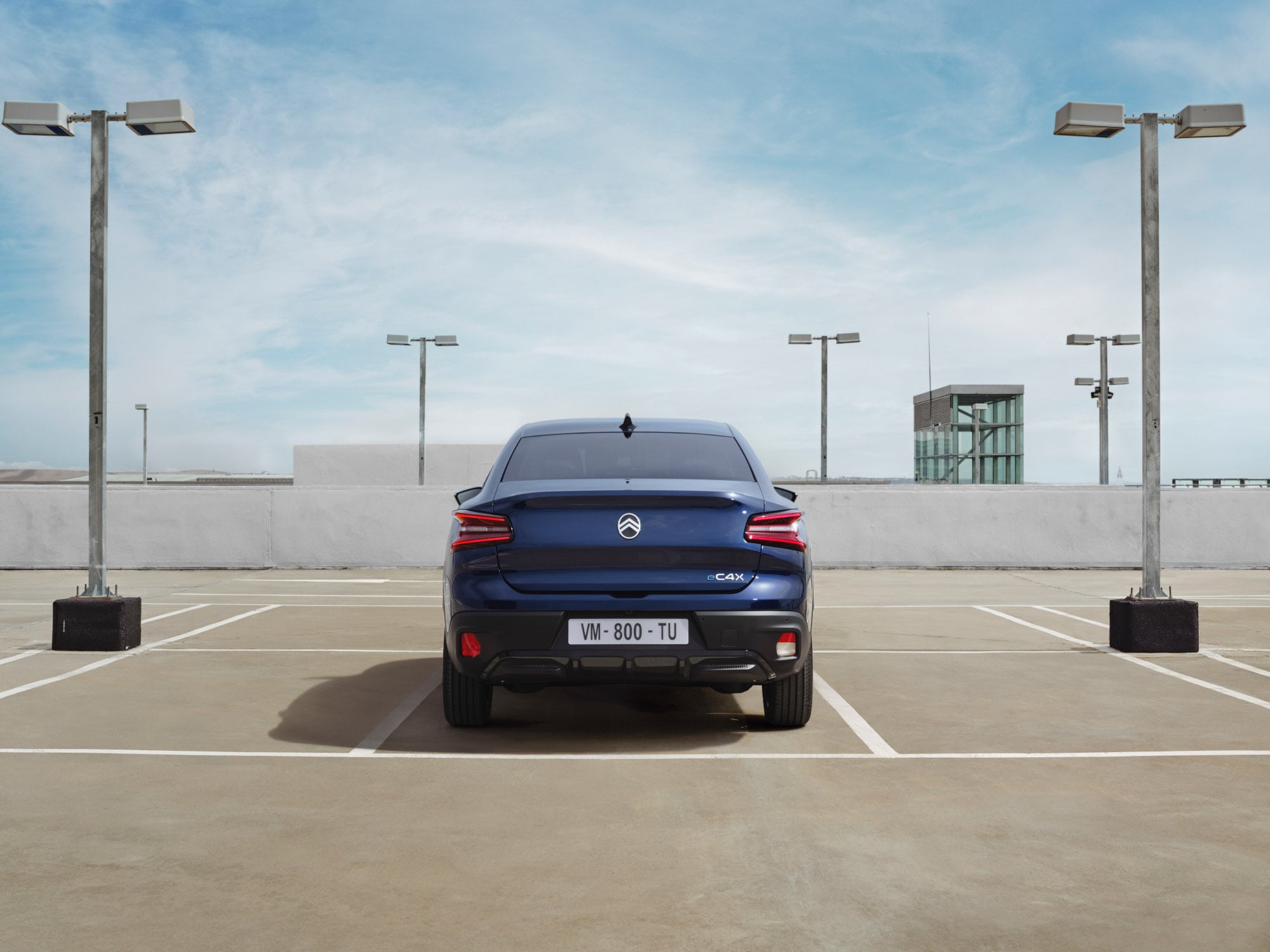 Vista trasera del Citroën C4 X en parking de azotea mostrando diseño fastback distintivo para una movilidad elegante y asequible.