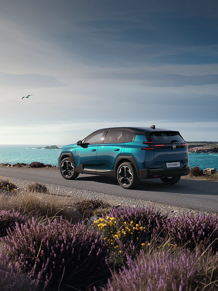 Vista de tres cuartos trasera del Citroën C5 Aircross Emeraude muestra las distintivas luces LED traseras Light Wings del C5 Aircross, SUV familiar en un trayecto costero