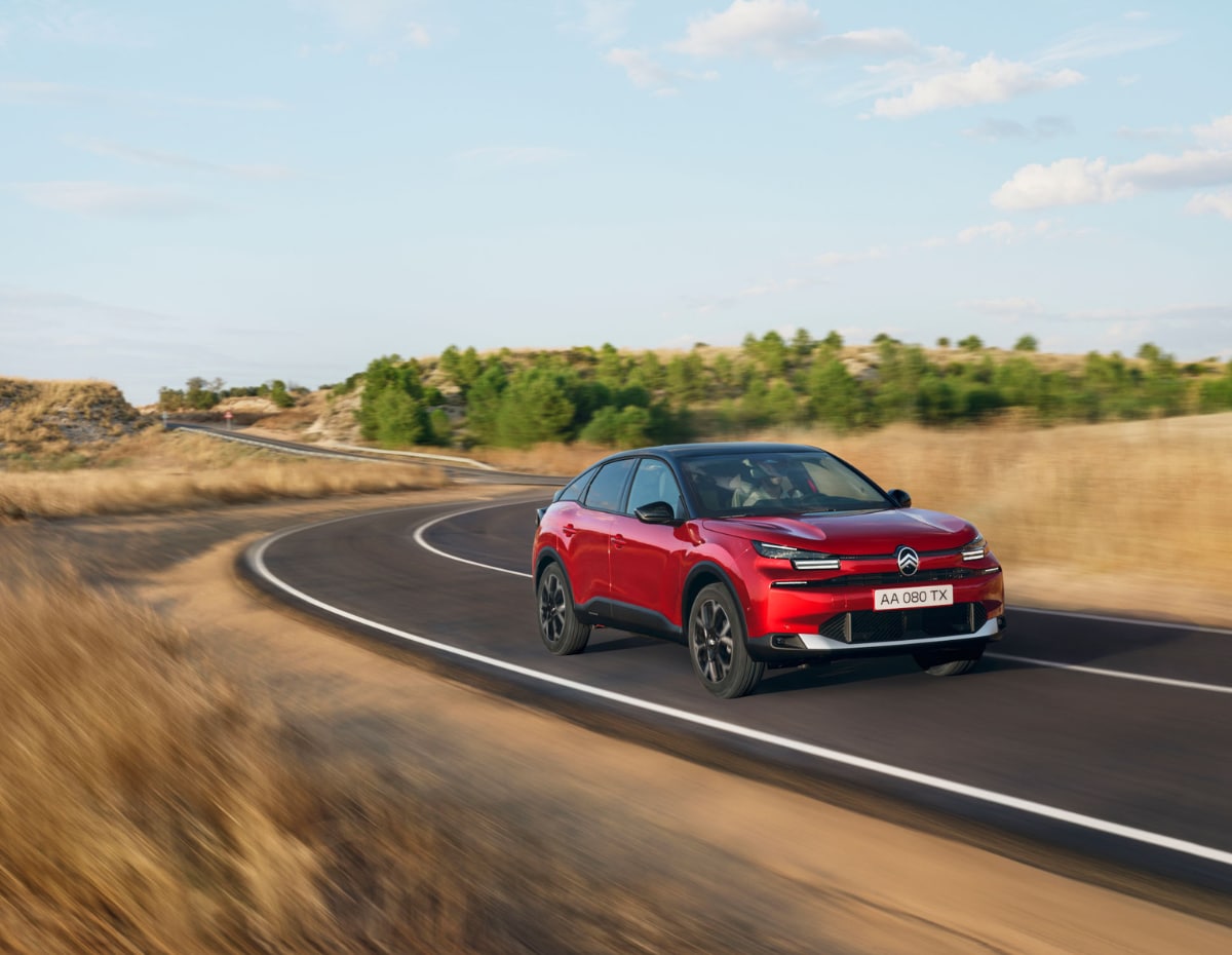 Three‑quarter front view ë-C4 Elixir Red driving on an open road illustrating immediate stock availability